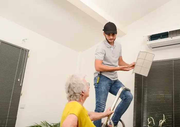 handsome-young-man-electrician-cleaning-air-filter-indoor-unit-air-conditioning-system-client-house-with-senior-woman-power-repair-team
